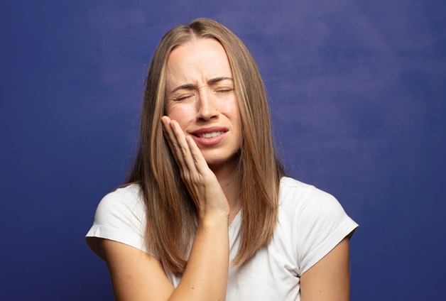 A girl is holding her cheek because of wisdom tooth pain.