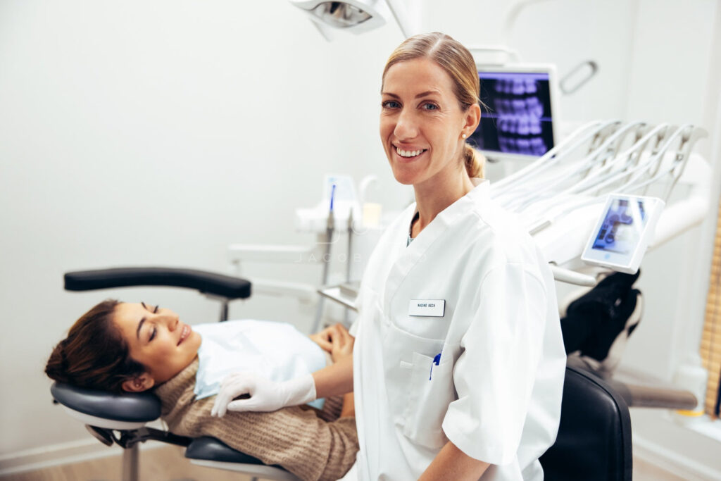 A dentist standing beside her female patient
